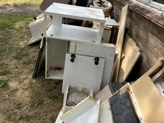 Rubbish Collection in Greenwich 3 Old white kitchen units and boards stacked on a lawn, ready for collection